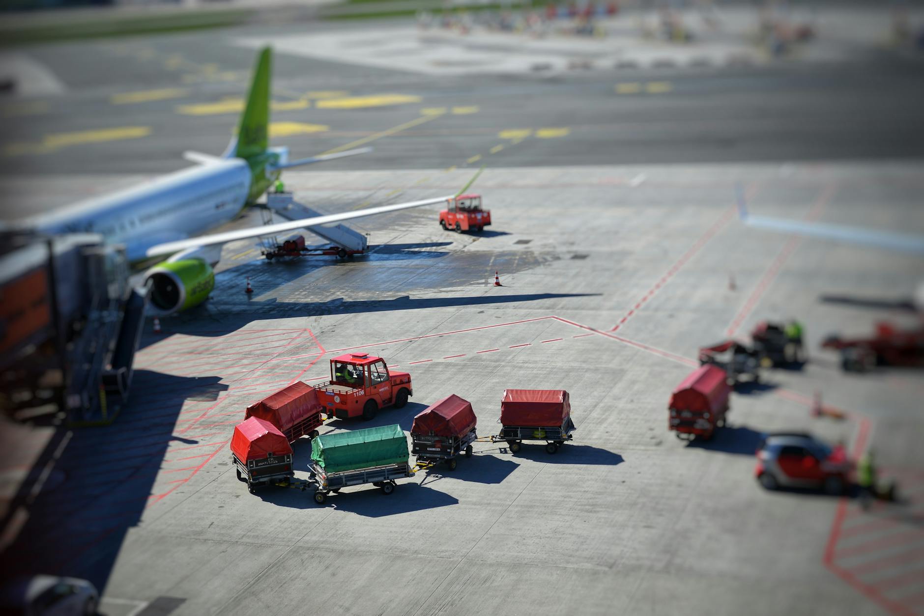 Sunlit airplane and baggage carts on airport tarmac