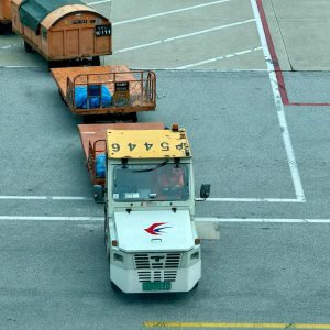 Tow tractor pulling cargo containers on airport tarmac