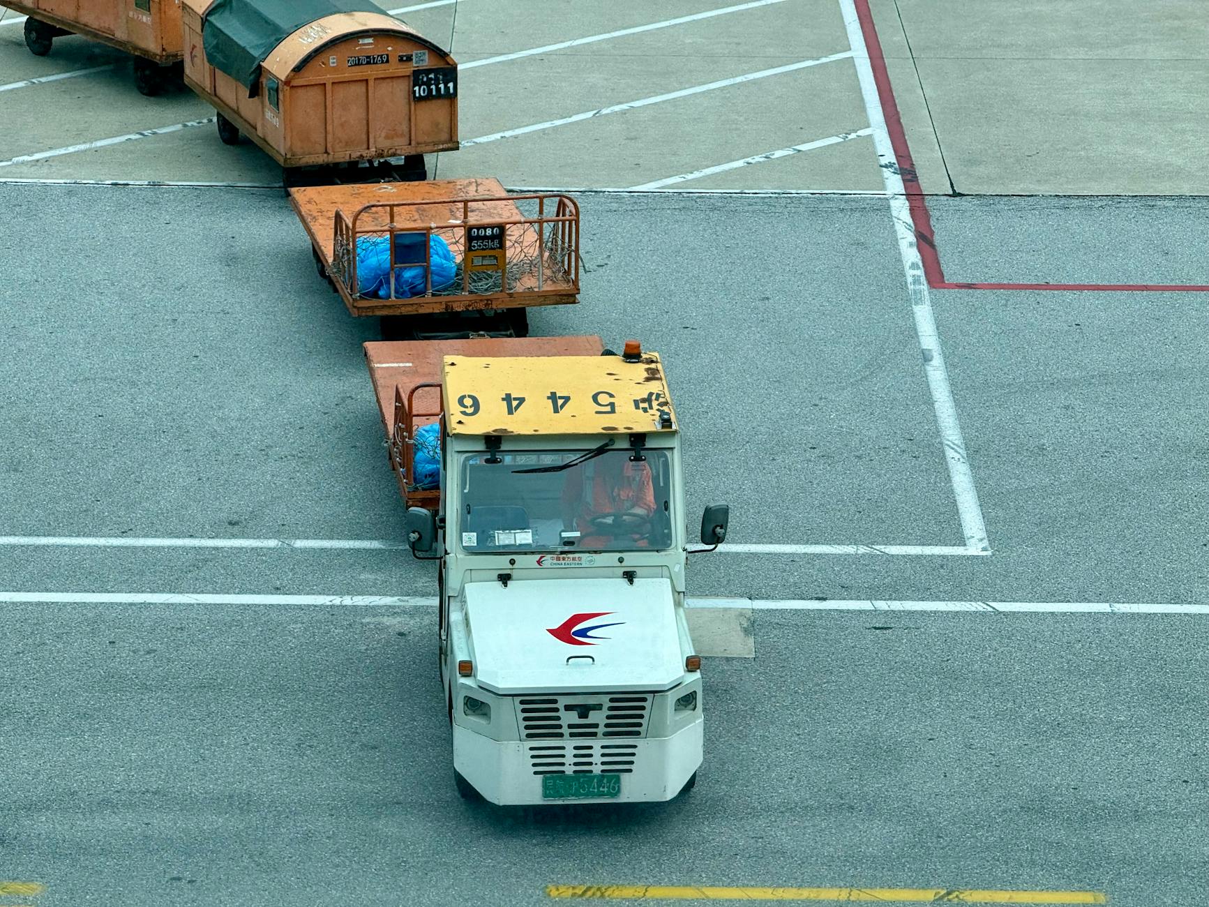 Tow tractor pulling cargo containers on airport tarmac