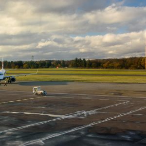 Commercial airplane stationed on tarmac under bright sky