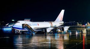 Cargo airplane being loaded at night at airport with visible operations