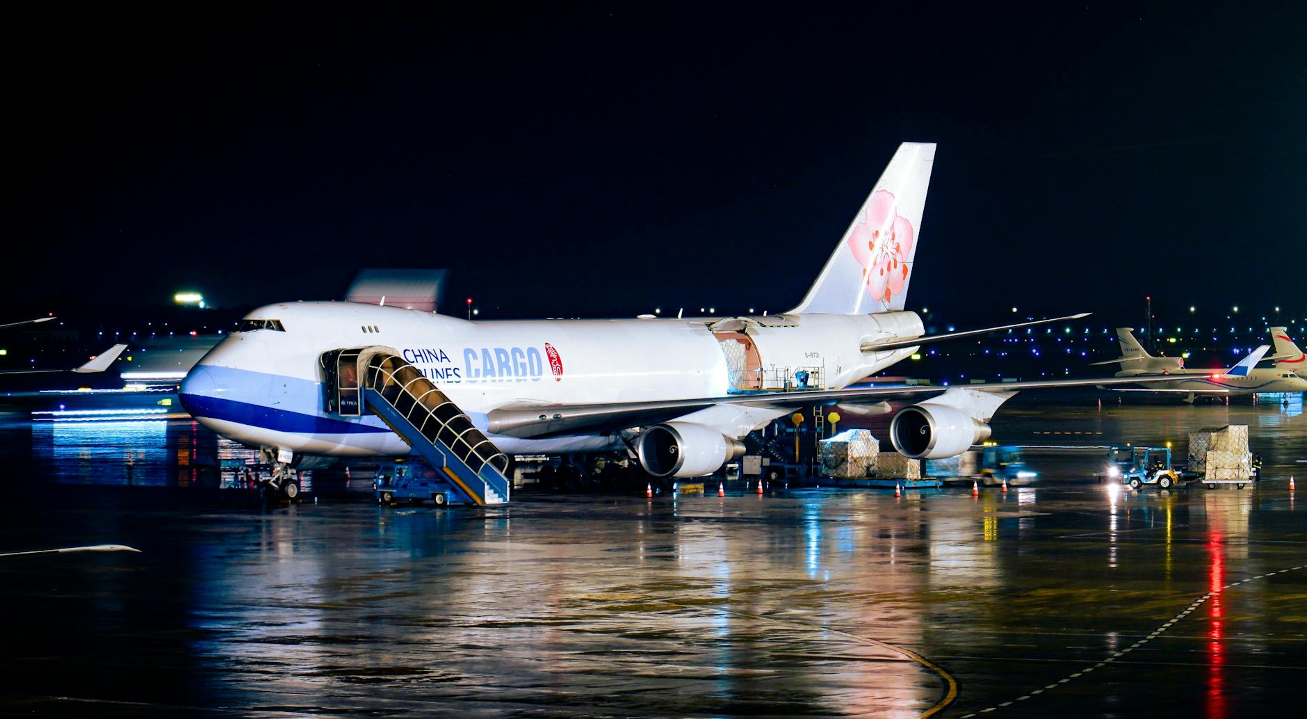 Cargo airplane being loaded at night at airport with visible operations