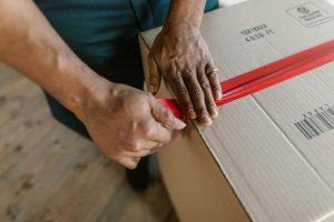Hands sealing cardboard box with tape for air freight shipping - complete packing guide with requirements