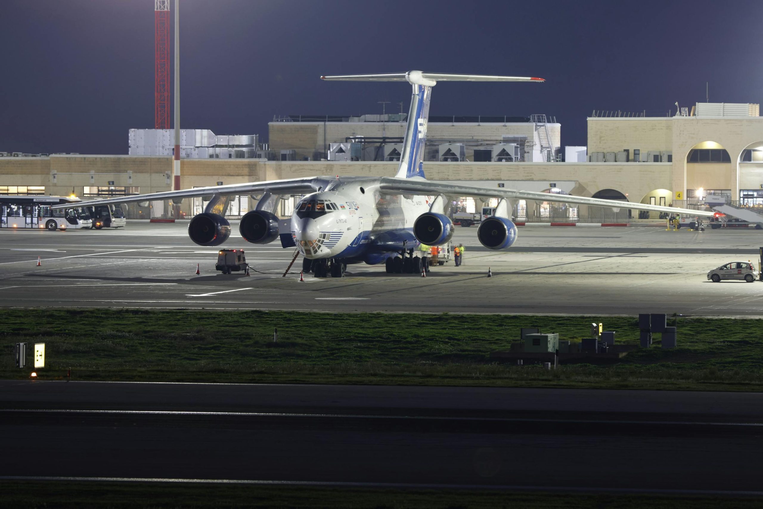 Large cargo aircraft parked on airport runway at night under bright lights, air freight operations