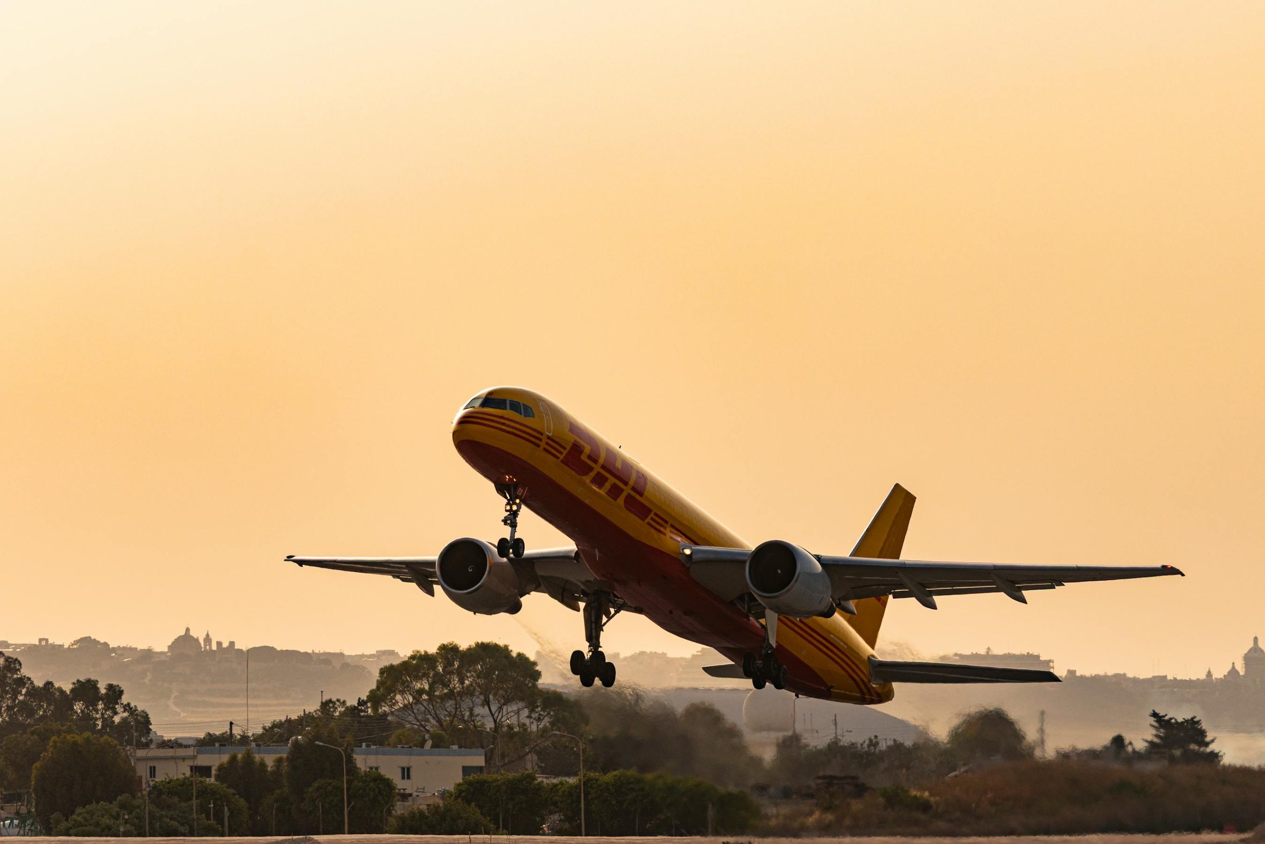 DHL cargo plane taking off against a golden sunset sky, showcasing air freight aviation in action